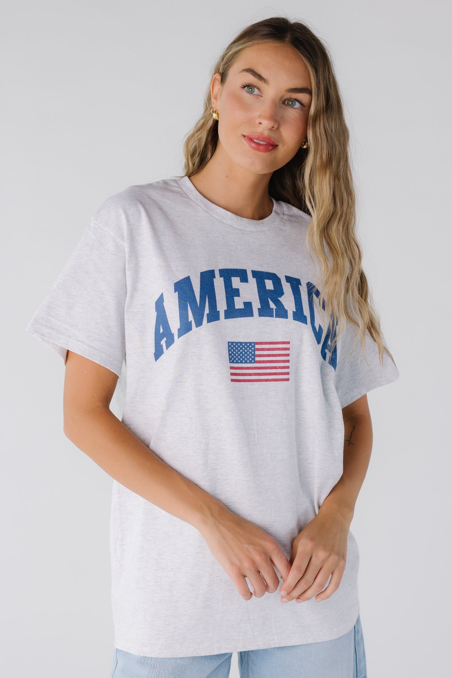 Modest light grey tee with crew neckline and short sleeves  and large front America and flag graphic