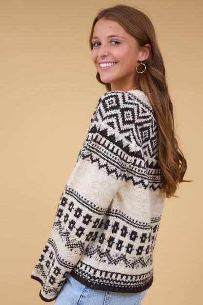 A side view of a woman wearing an oatmeal & black norcid sweater with loose sleeves.
