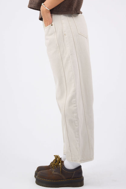 A side view of a woman wearing a pair of off white barrel jeans with side panels and dark contrasting stitching.