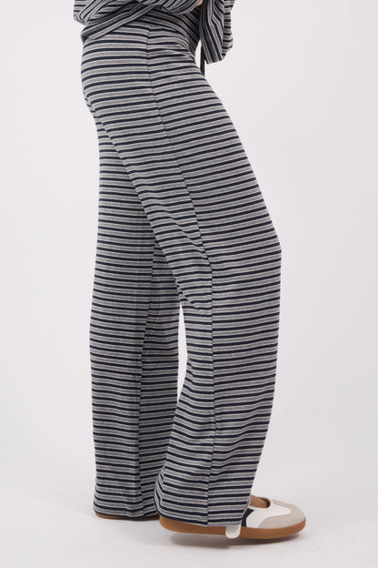 Side view of a woman wearing a pair of navy & grey stripe wide leg pants.