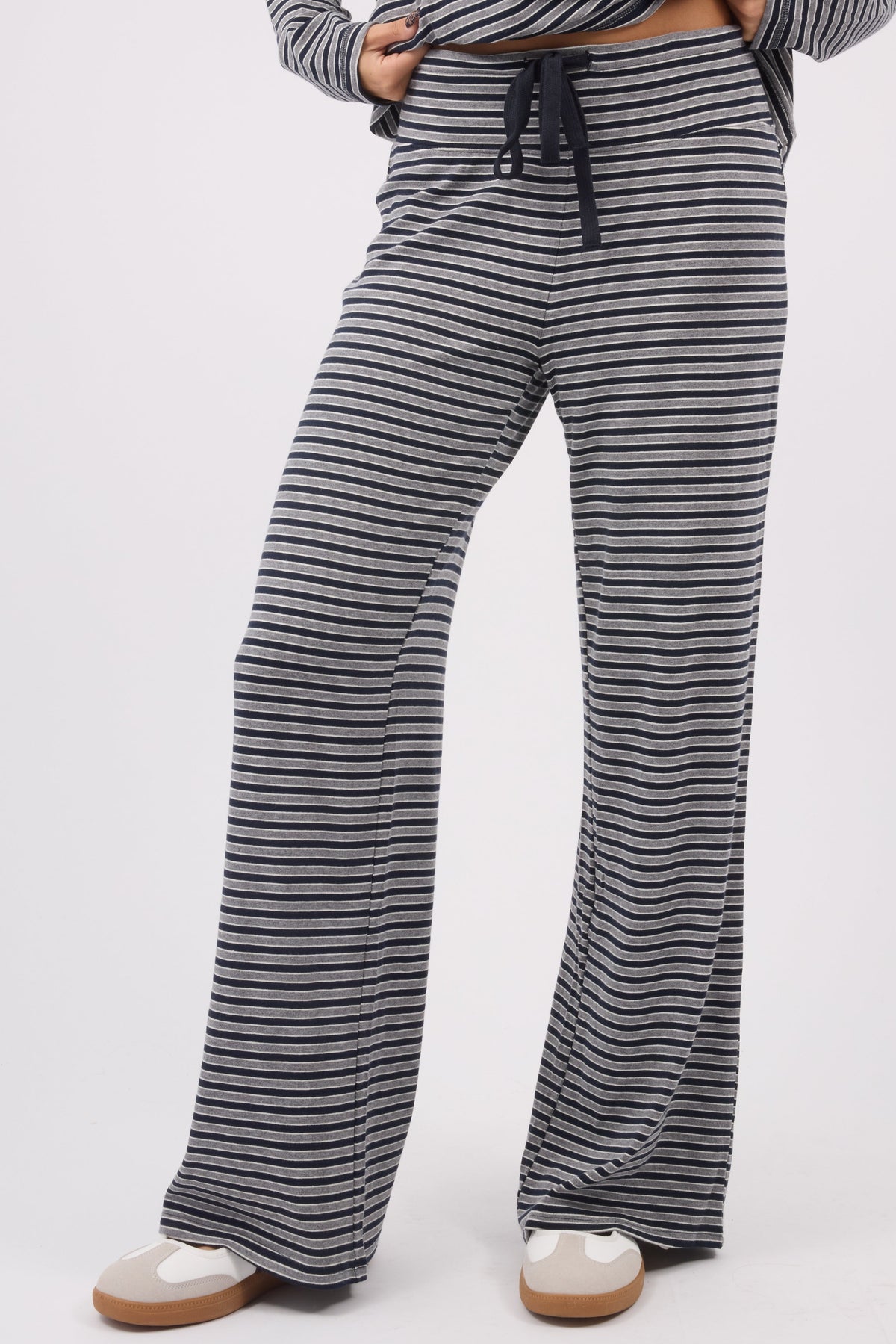 A young woman wearing a modest pair of stripe knit pants with a wide cut leg and elastic & drawstring waistband.
