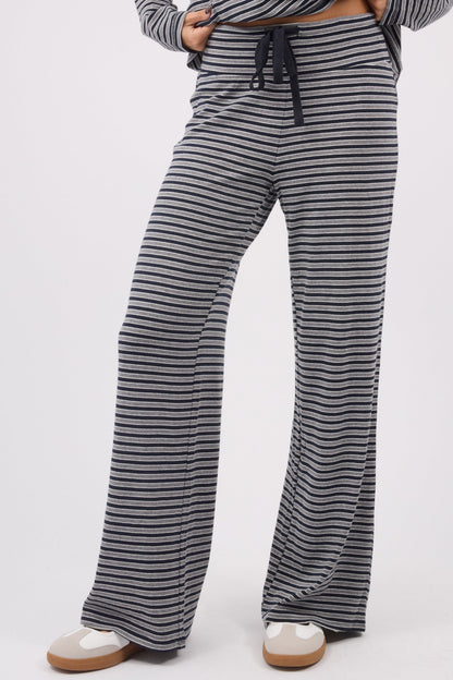 A young woman wearing a modest pair of stripe knit pants with a wide cut leg and elastic & drawstring waistband.