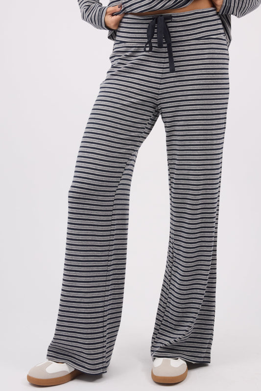 A young woman wearing a modest pair of stripe knit pants with a wide cut leg and elastic & drawstring waistband.