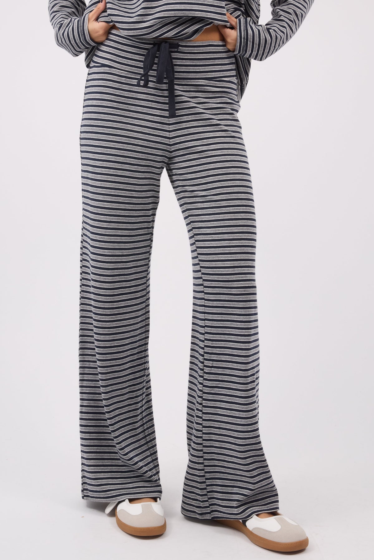A woman wearing a soft stretchy pair of navy & grey wide leg lounge pants.