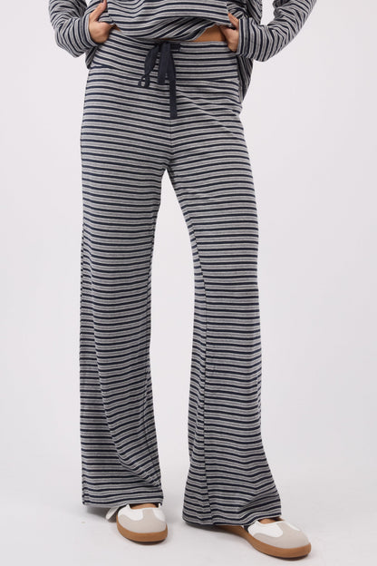 A woman wearing a soft stretchy pair of navy & grey wide leg lounge pants.