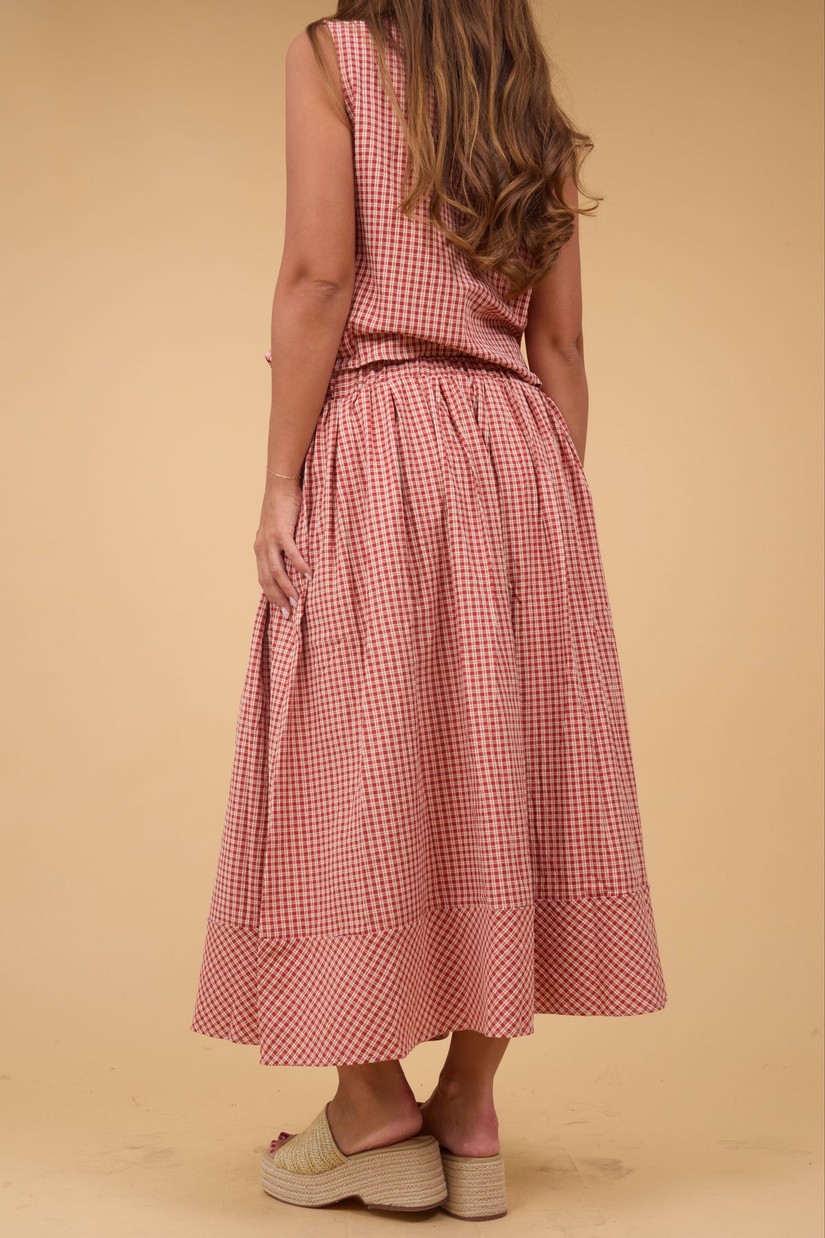 Back view of a woman wearing a red plaid midi skirt with a matching sleeveless top.