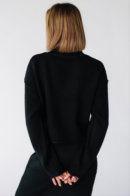Back view of a woman wearing a black long sleeve sweater and skirt set