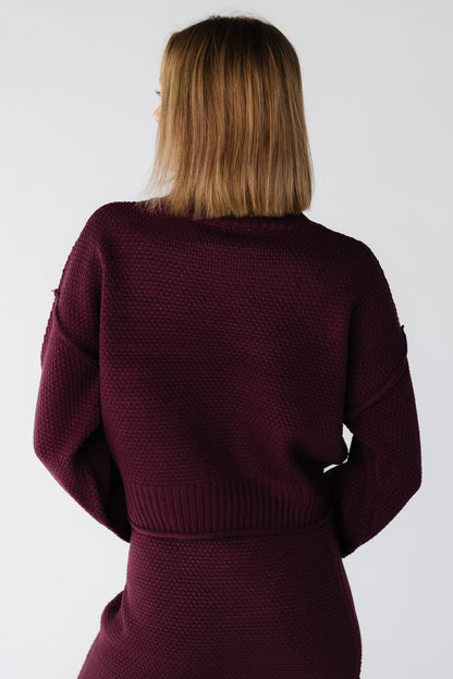 Back view of a woman wearing a long sleeve textured 2 piece sweater and skirt set