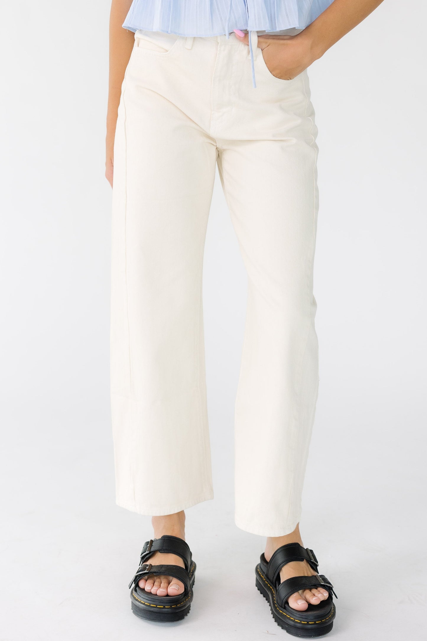 Woman wearing a pair of modest wide leg barrel jeans in almond off white with pockets and a mid rise waist.