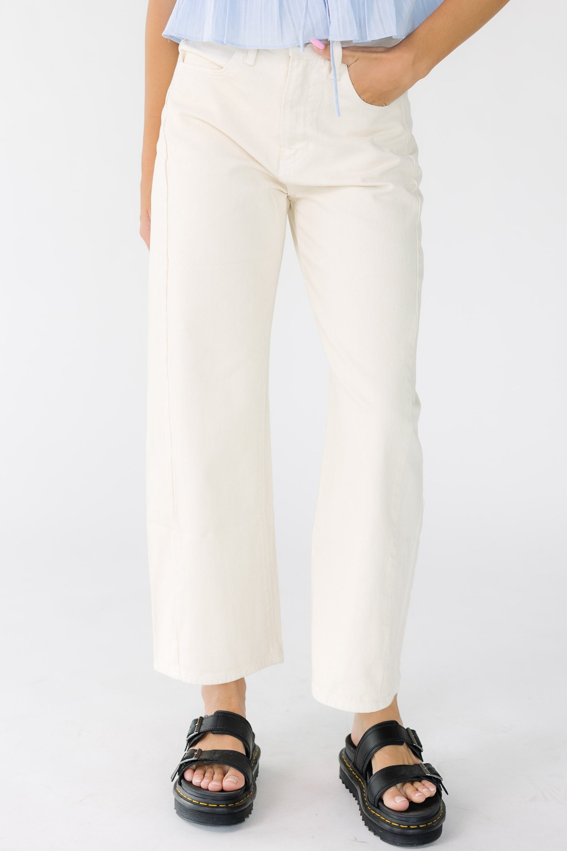 Woman wearing a pair of modest wide leg barrel jeans in almond off white with pockets and a mid rise waist.
