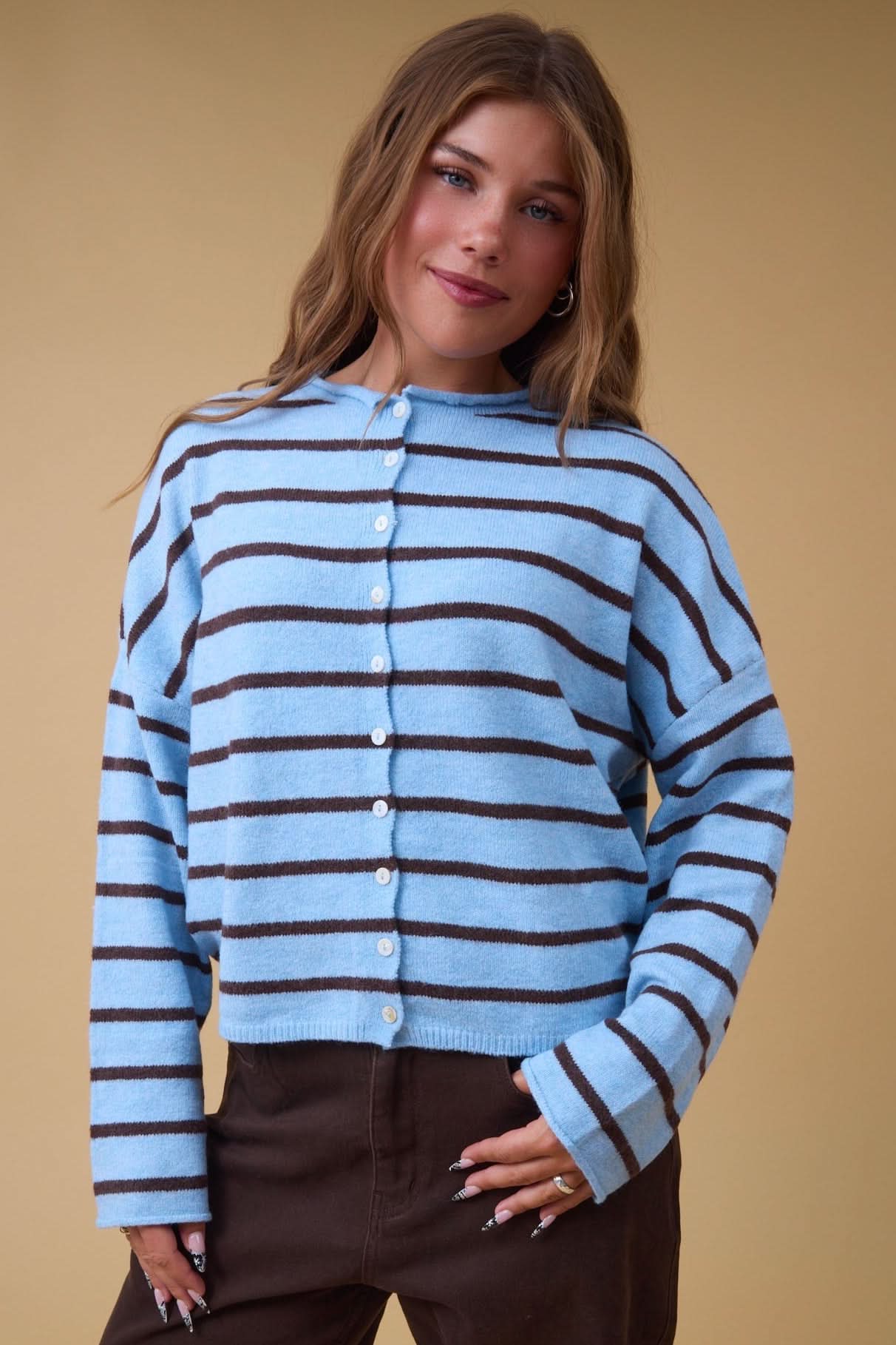 Young woman wearing a modest light blue & brown stripe button down cardigan with long sleeves and a rolled neckline.
