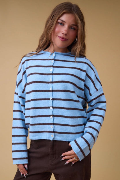 Young woman wearing a modest light blue & brown stripe button down cardigan with long sleeves and a rolled neckline.