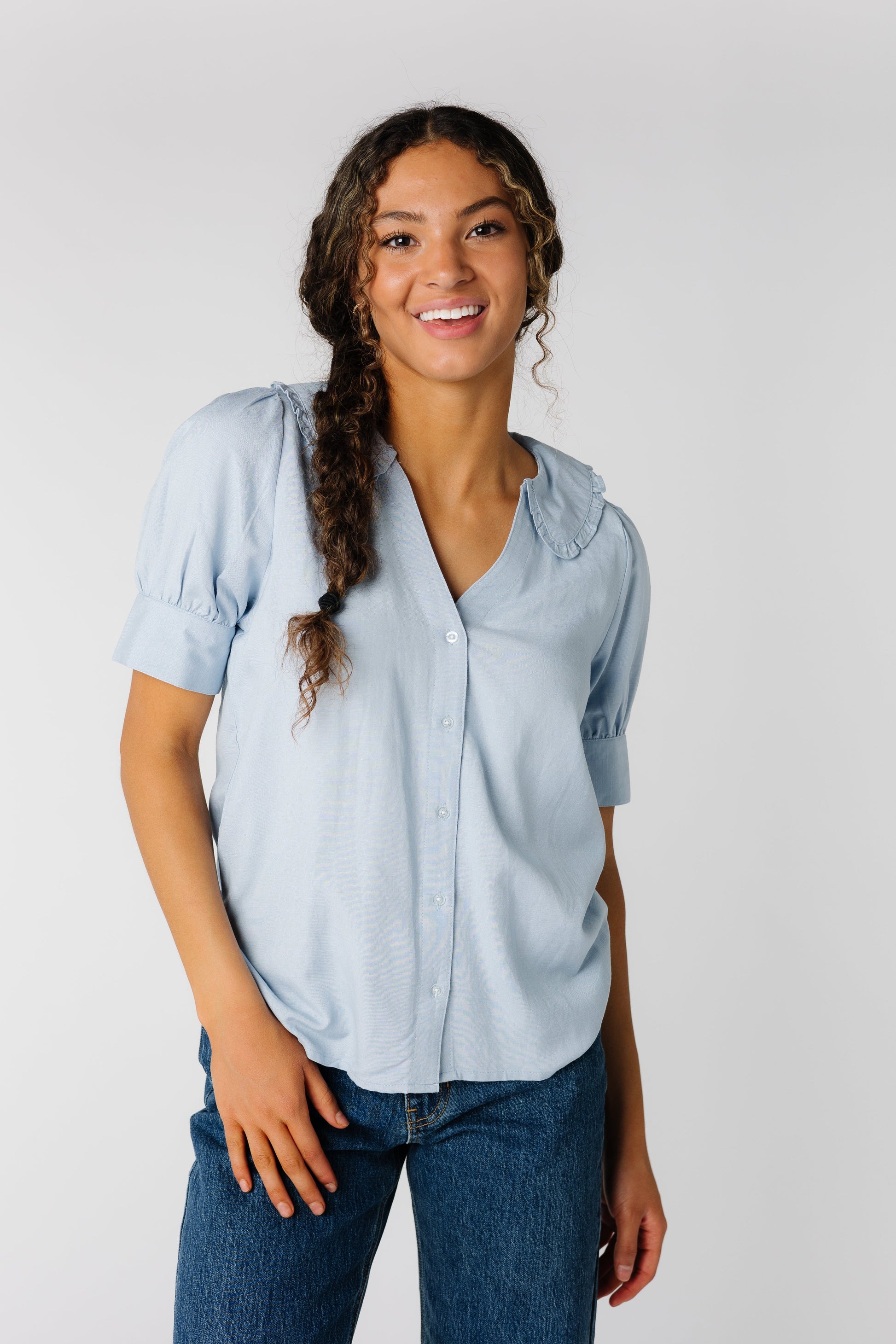 Light blue button down top with V-neckline and ruffled collar with short sleeves