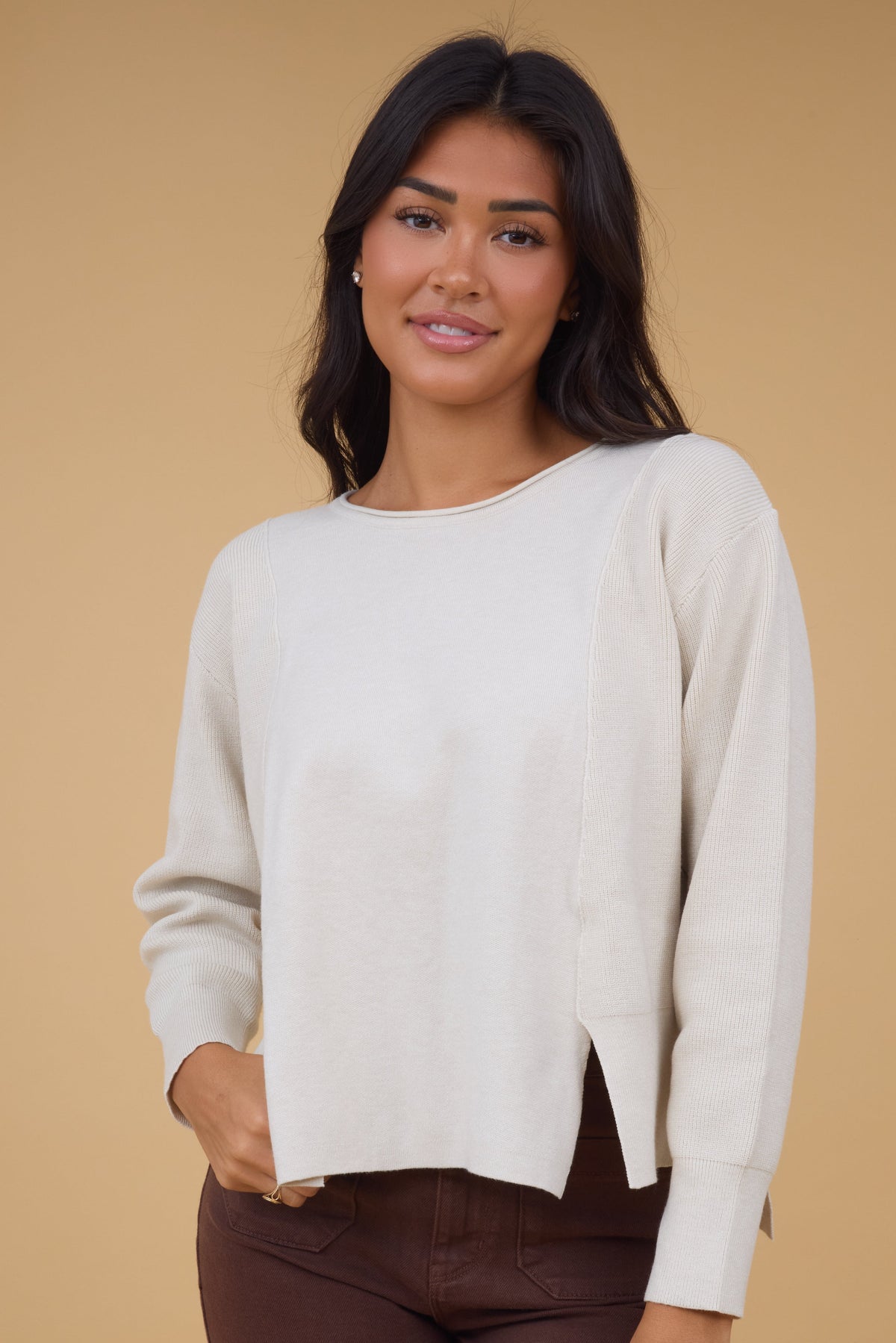 Young woman wearing a modest cream long sleeve sweater top with a boat neckline.