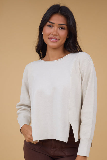 Young woman wearing a modest cream long sleeve sweater top with a boat neckline.