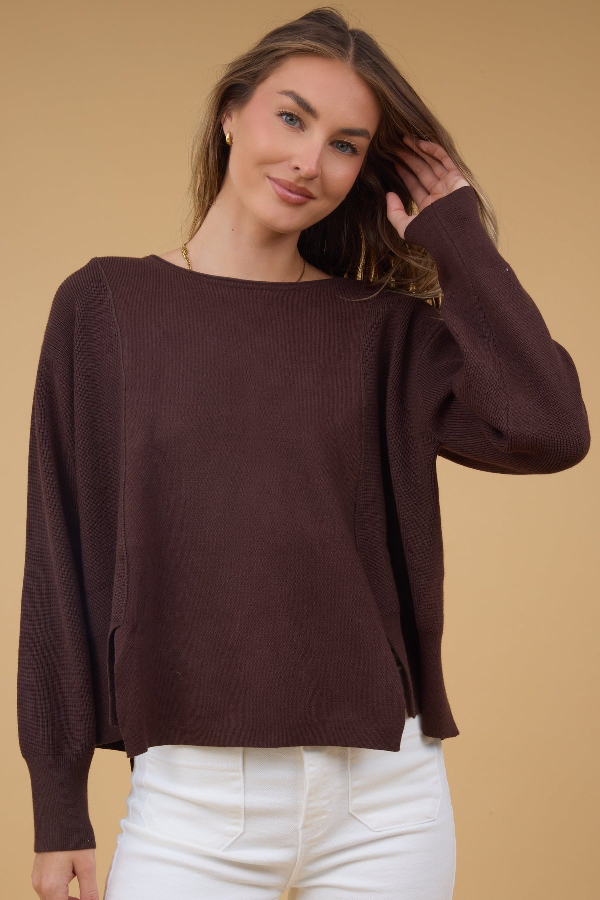 Young woman wearing a modest brown loose fitting sweater top with a boat neckline and long sleeves.