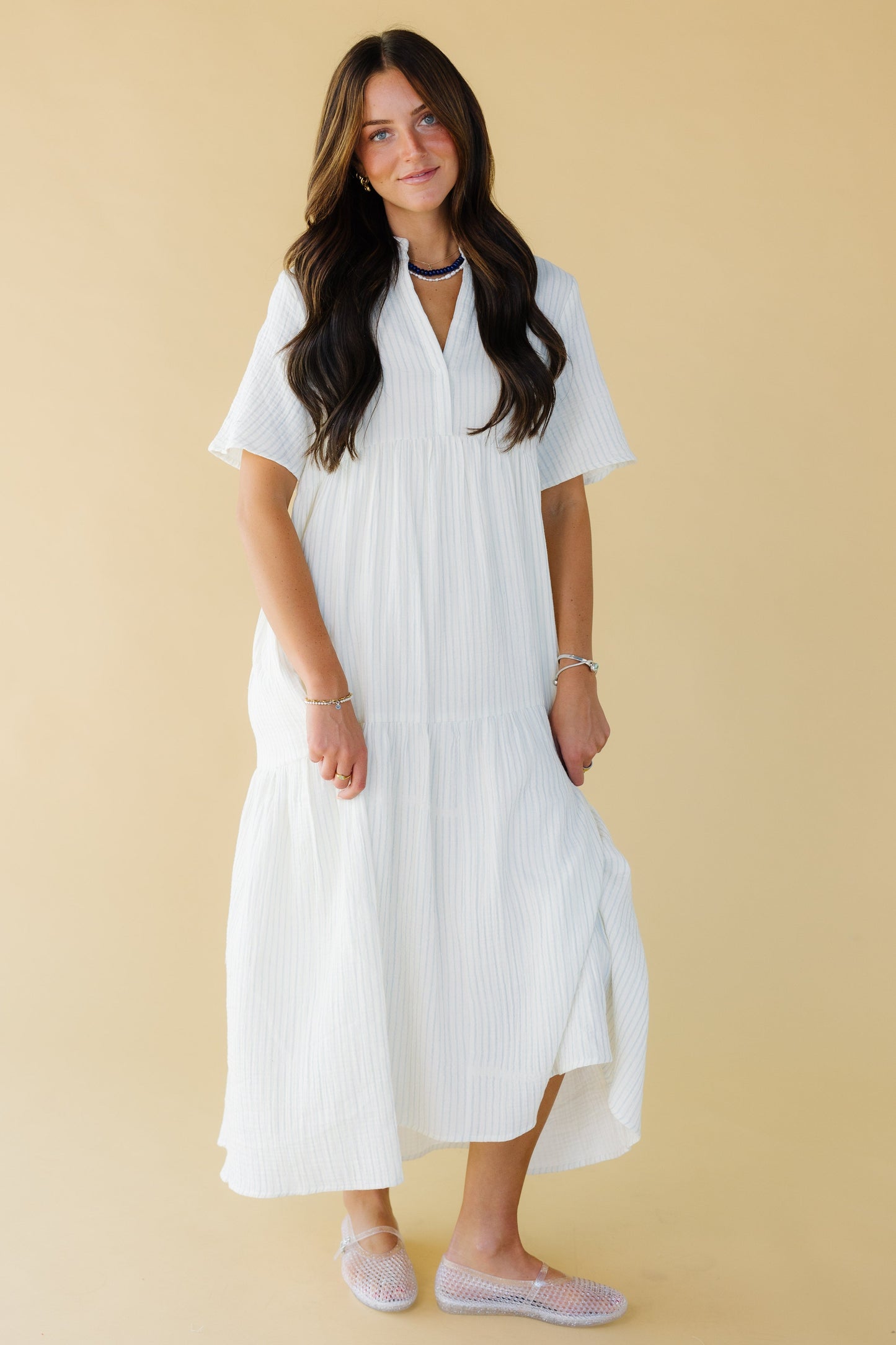 Young woman wearing a modest white & blue stripe midi-maxi dress with a v-neckline, short sleeves and a wide bottom ruffle.