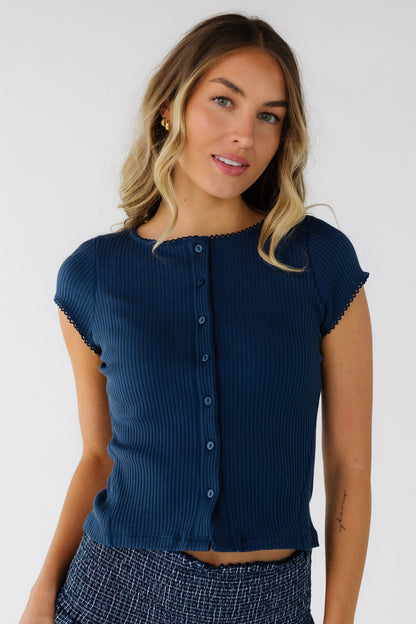 Young woman wearing a modest close fitting rib knit button down top with lace edged neckline and short sleeves.