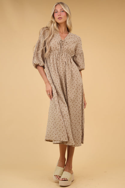 Young woman wearing a modest tan floral midi dress with a V-neckline, empire waist, V-neckline and half length sleeves.