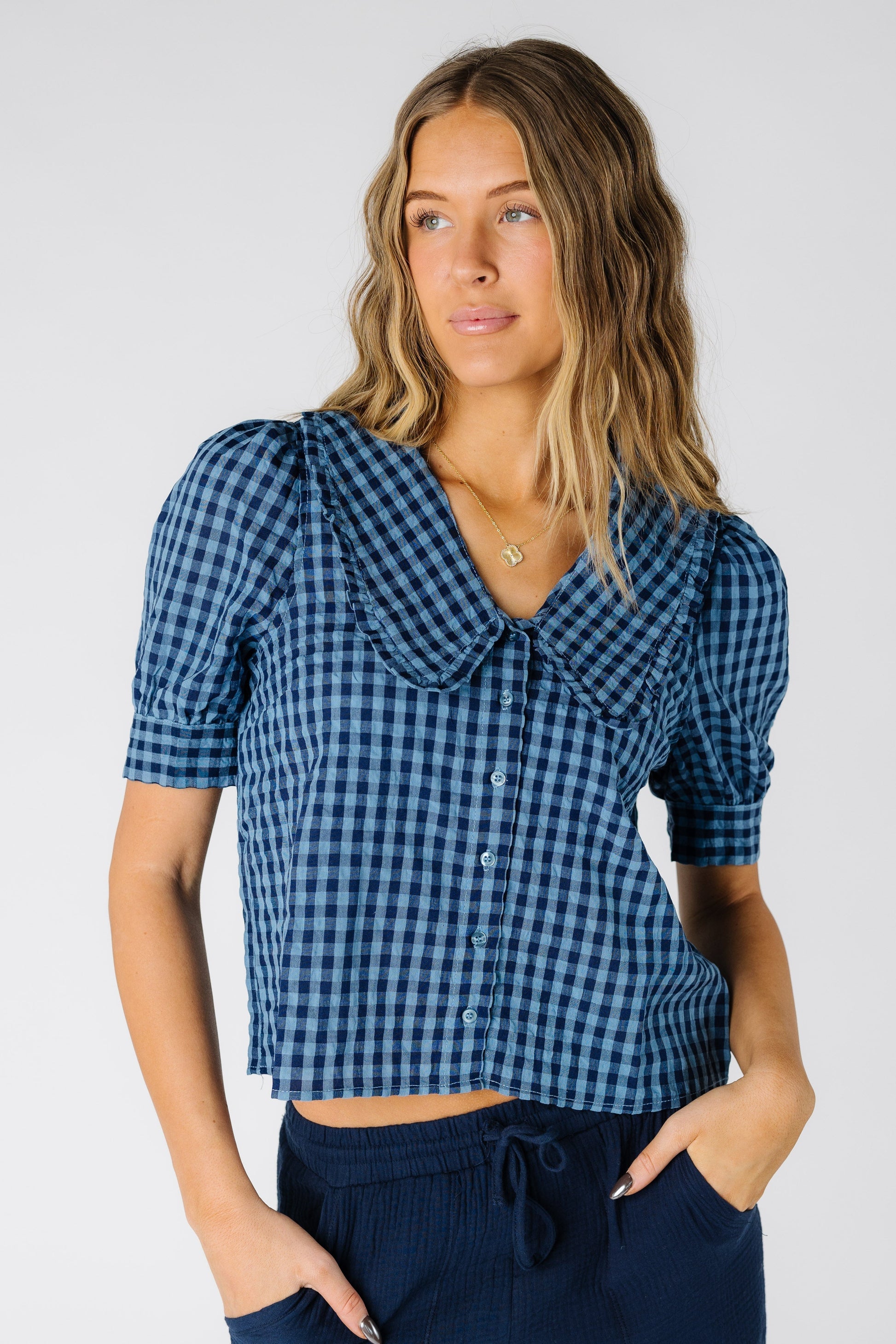 Woman wearing a modest  navy gingham top with a V-neckline with short puff sleeves