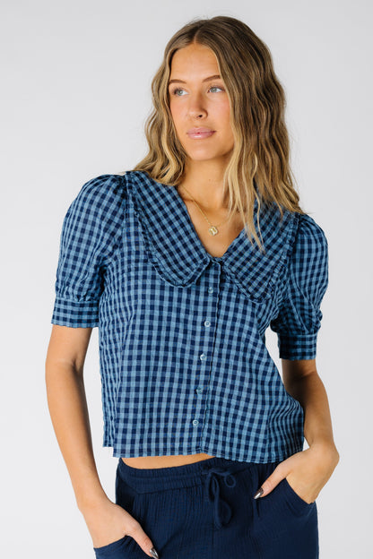 Woman wearing a modest  navy gingham top with a V-neckline with short puff sleeves