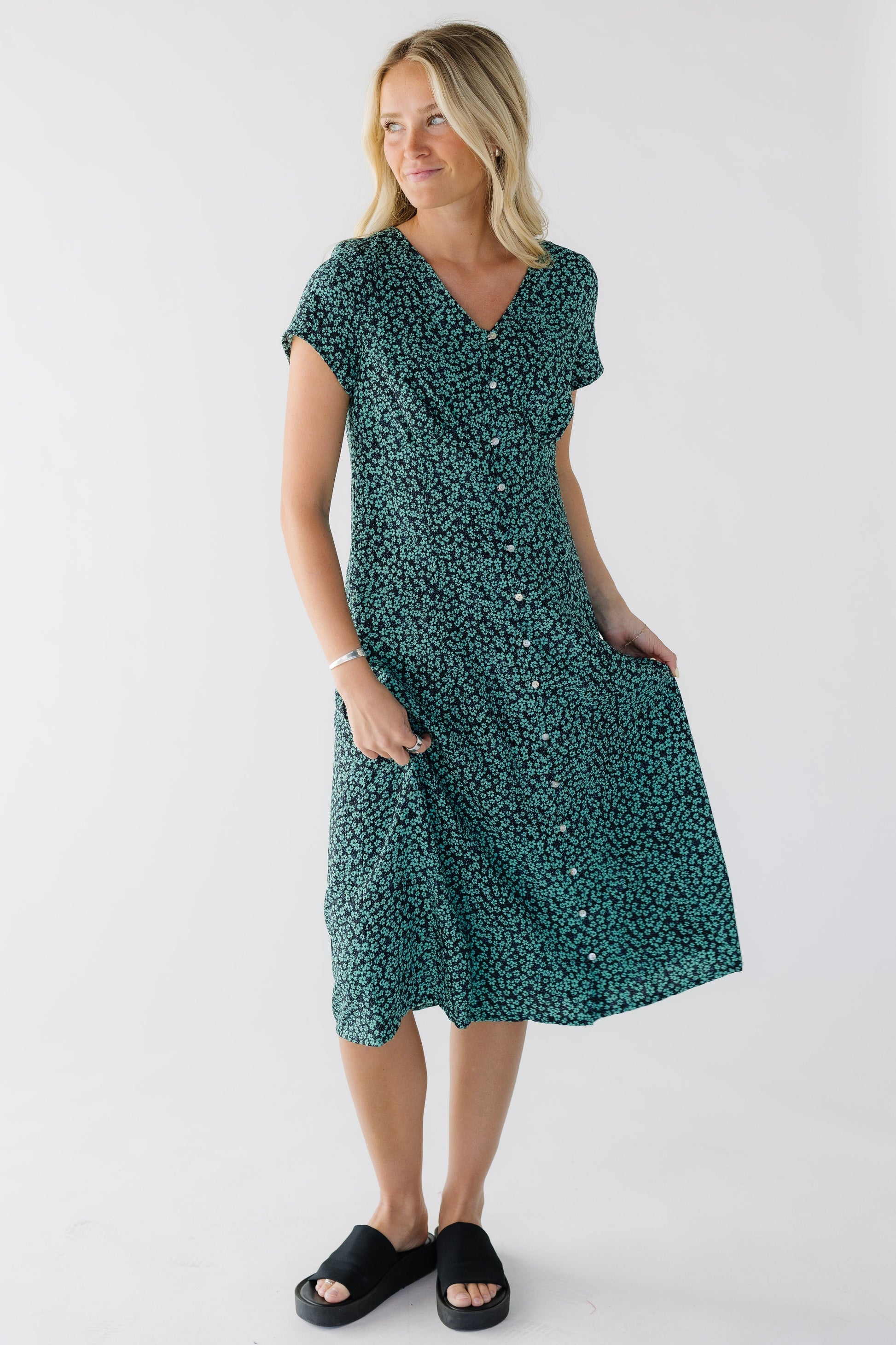 Young woman wearing a modest green floral print button down midi dress with a V-neckline and short sleeves.