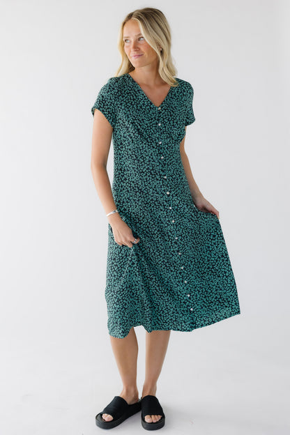 Young woman wearing a modest green floral print button down midi dress with a V-neckline and short sleeves.