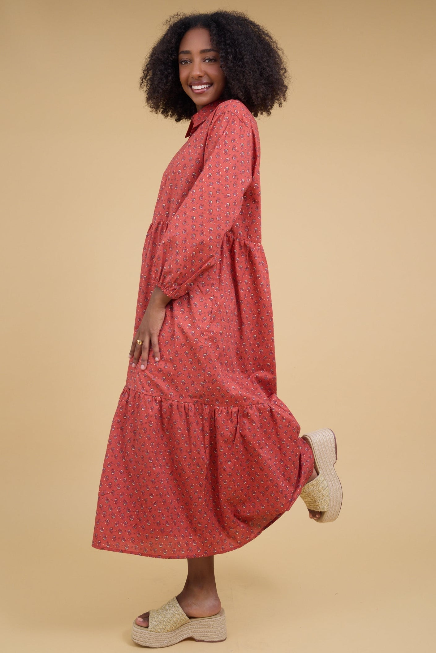 Young woman wearing a loose fitting midi dress with long sleeves and a pointed collar.