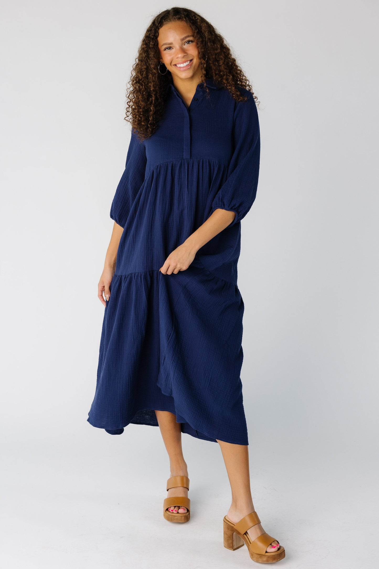 Teen girl wearing a modest navy midi dress with V-neckline, three quarters sleeves and tiered skirt