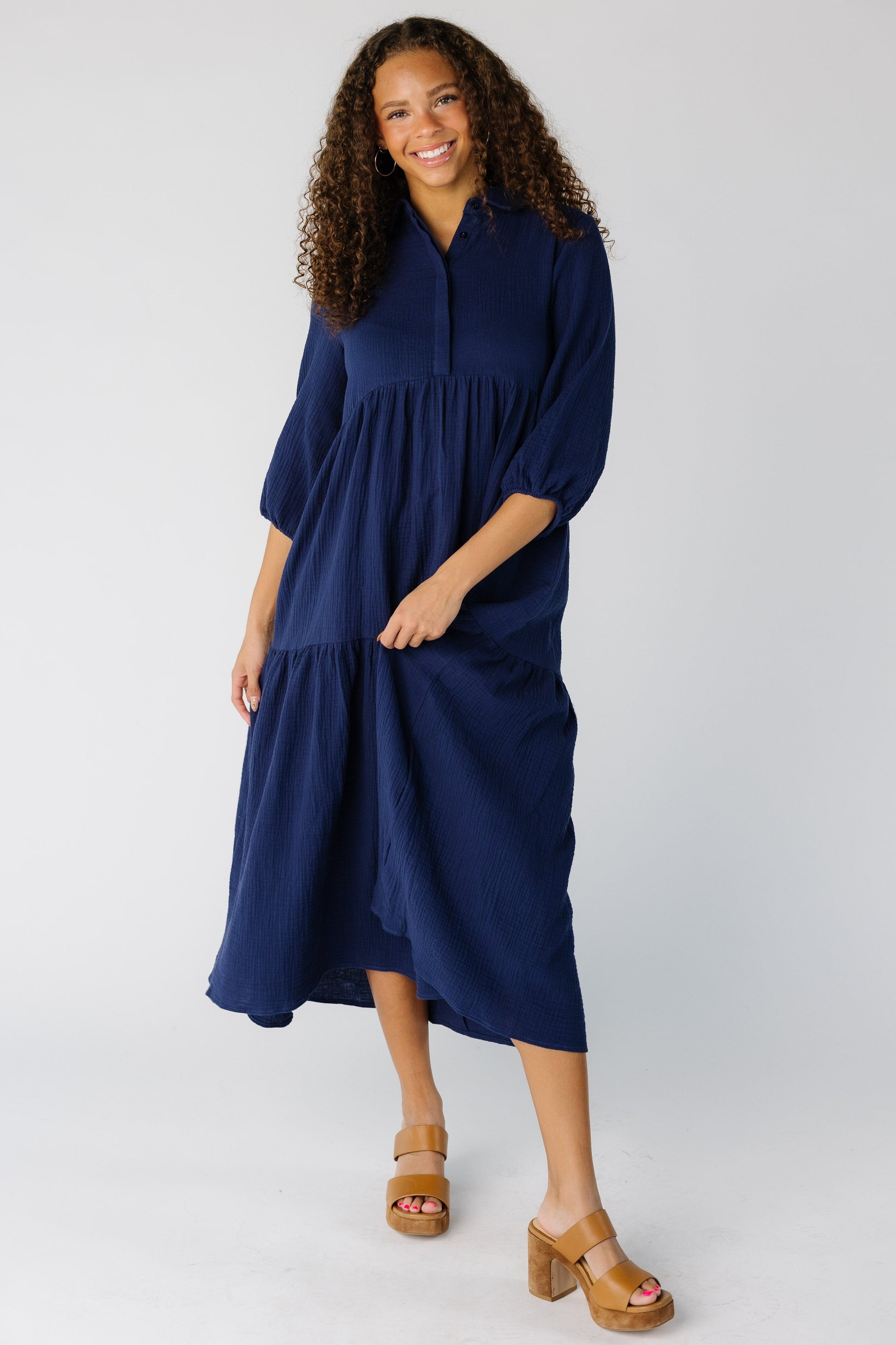 Teen girl wearing a modest navy midi dress with V-neckline, three quarters sleeves and tiered skirt