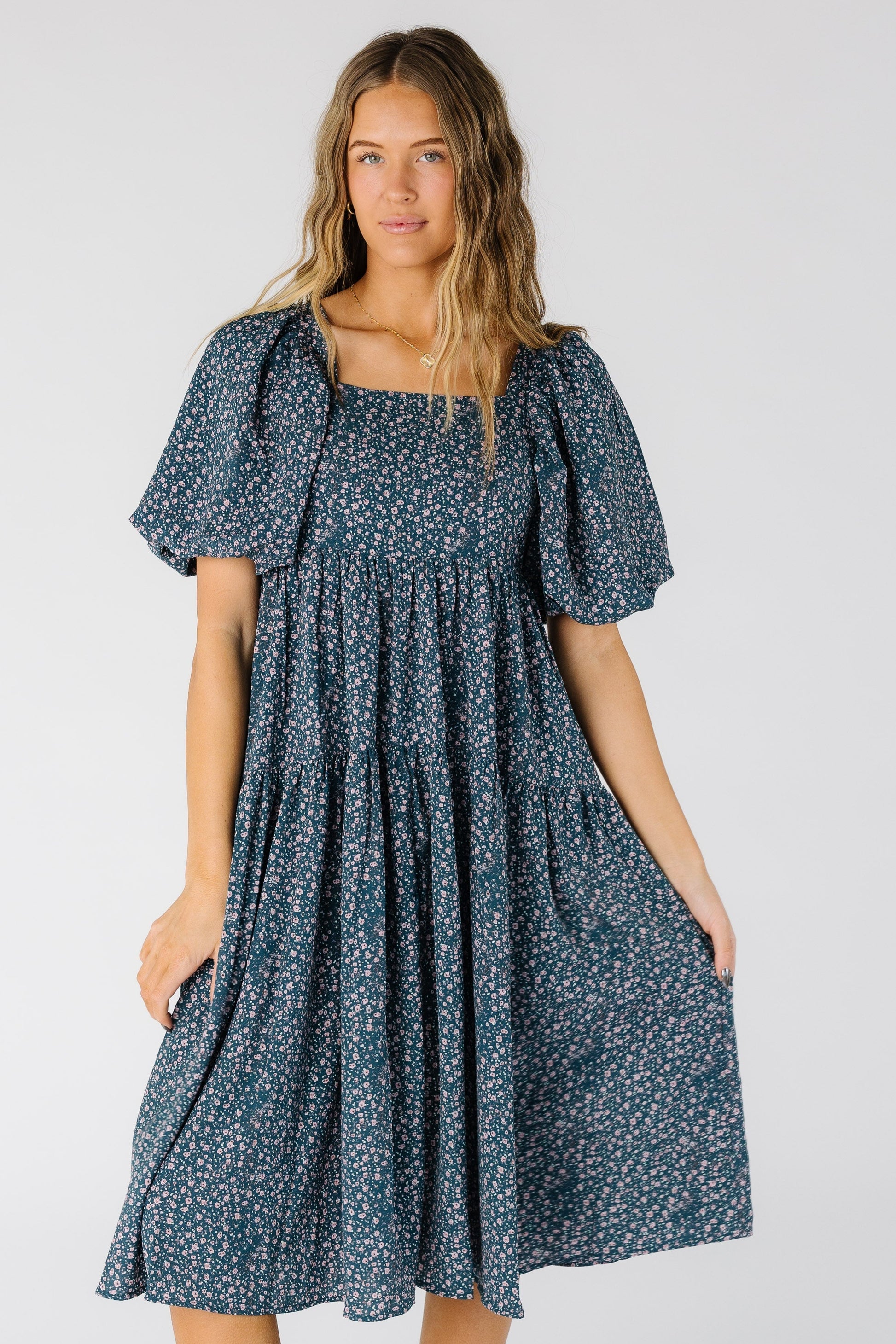 Woman wearing a modest blue floral print midi dress with a square neckline and short balloon sleeves
