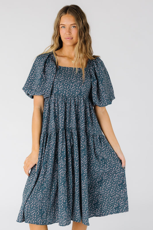 Woman wearing a modest blue floral print midi dress with a square neckline and short balloon sleeves