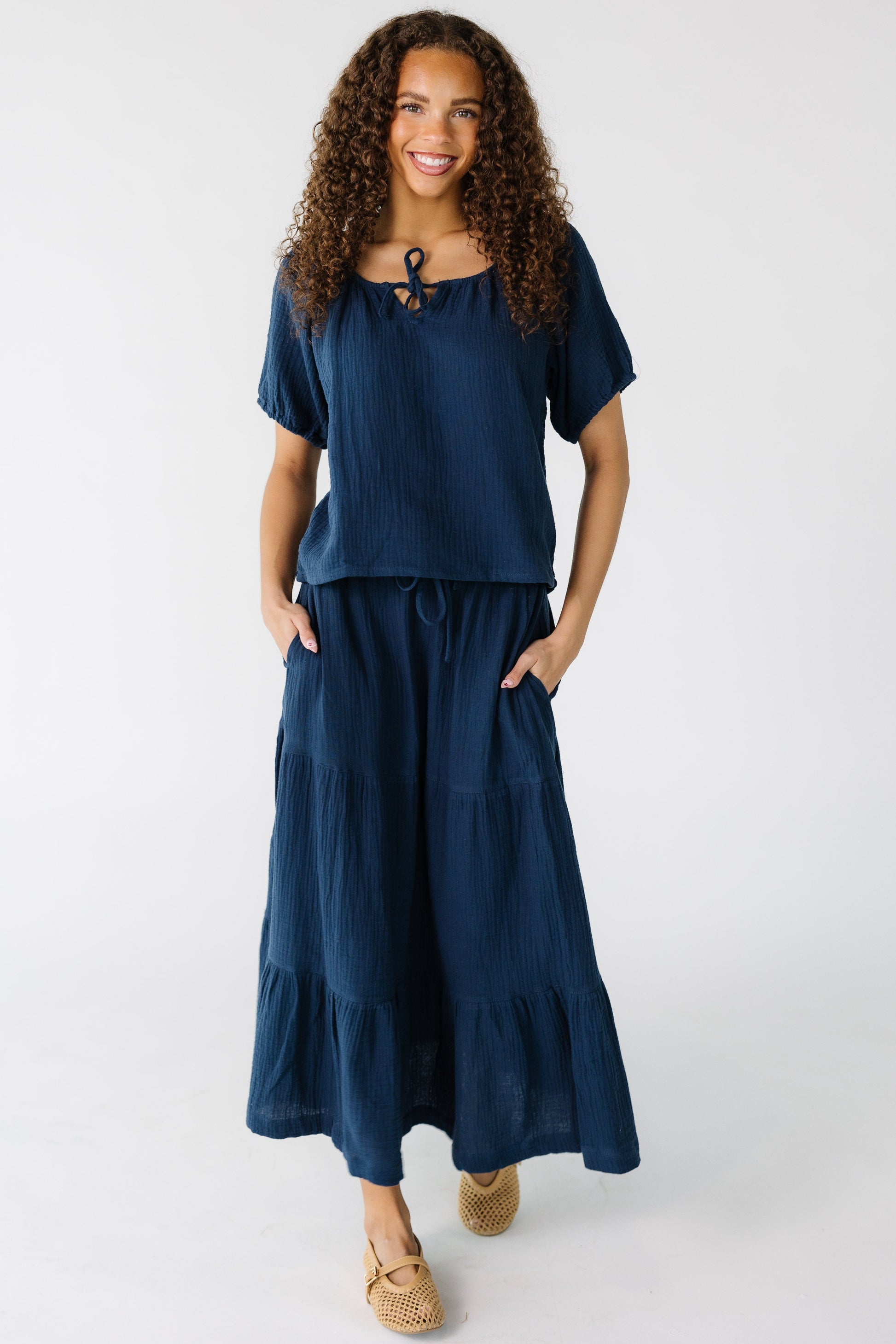 Teenage girl wearing a navy gauzy top with a round neckline and short sleeves.