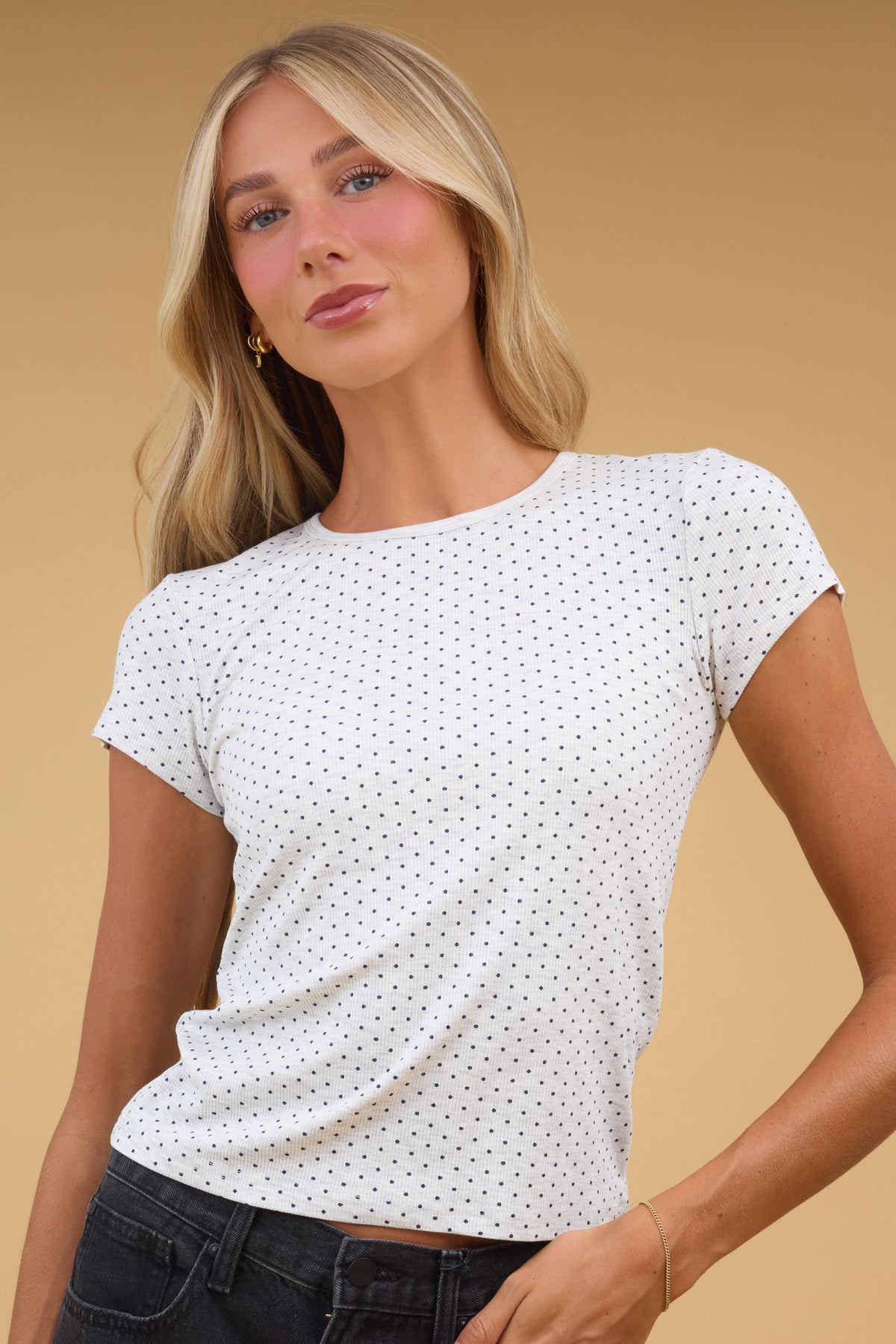 Young woman wearing a modest light grey and black polka dot tee with a round neckline and short cap sleeves.