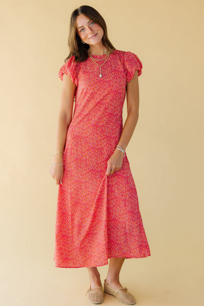 Young woman wearing a modest red floral midi dress with a round neckline and puffy cap sleeves.