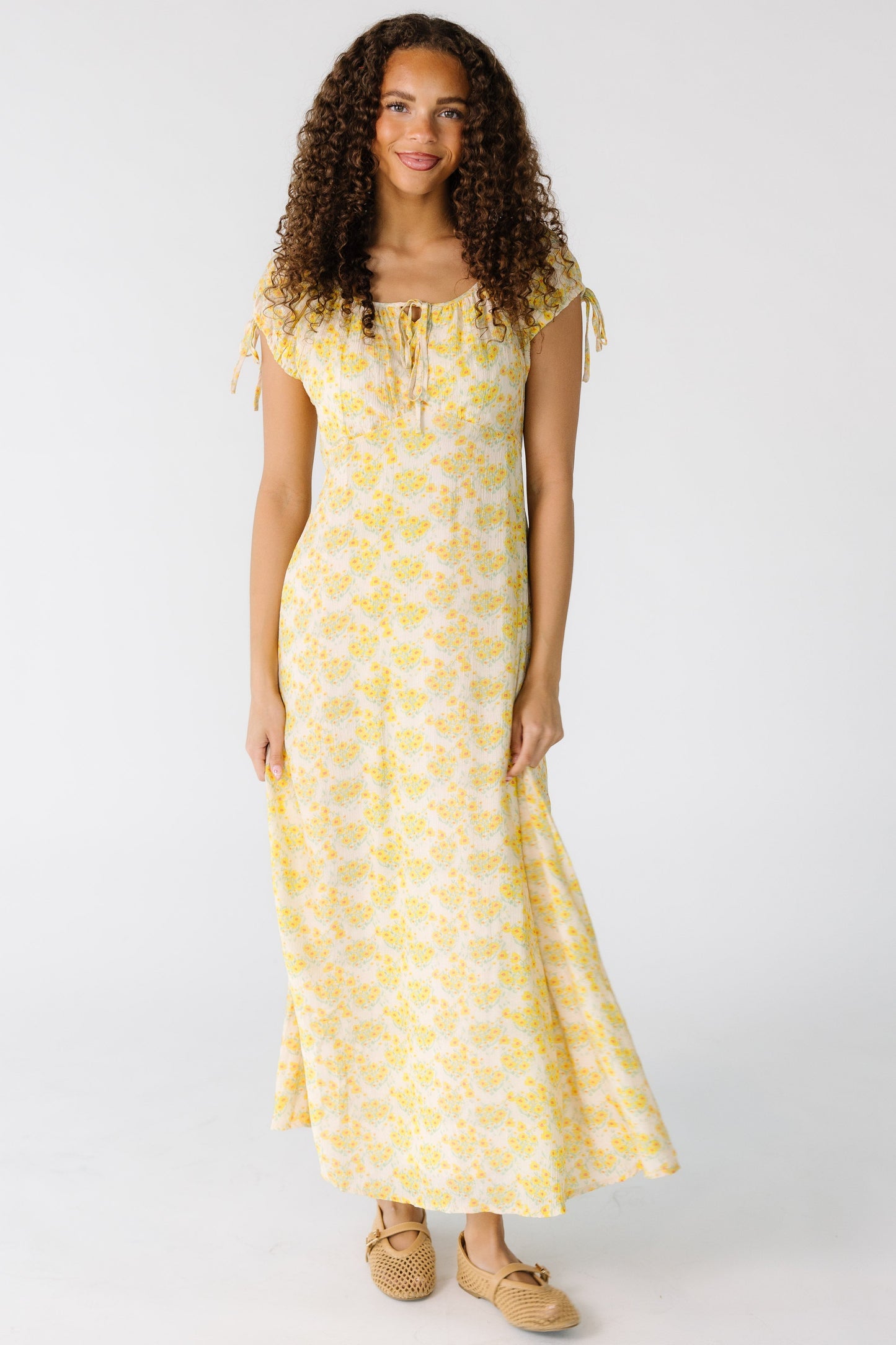 Teen girl wearing a modest yellow midi dress with a square neckline and short puff sleeves, and a pointed empire waist.