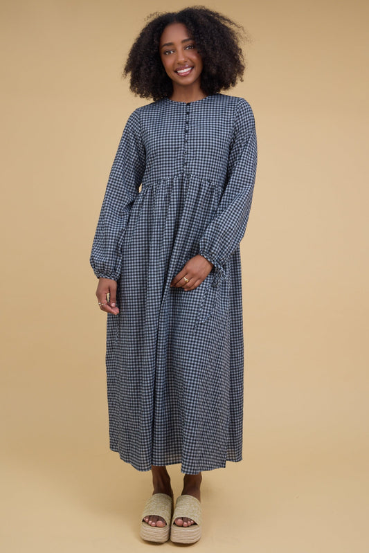 Young woman wearing a blue gingham midi dress wtih long sleeves and a button down bodice.