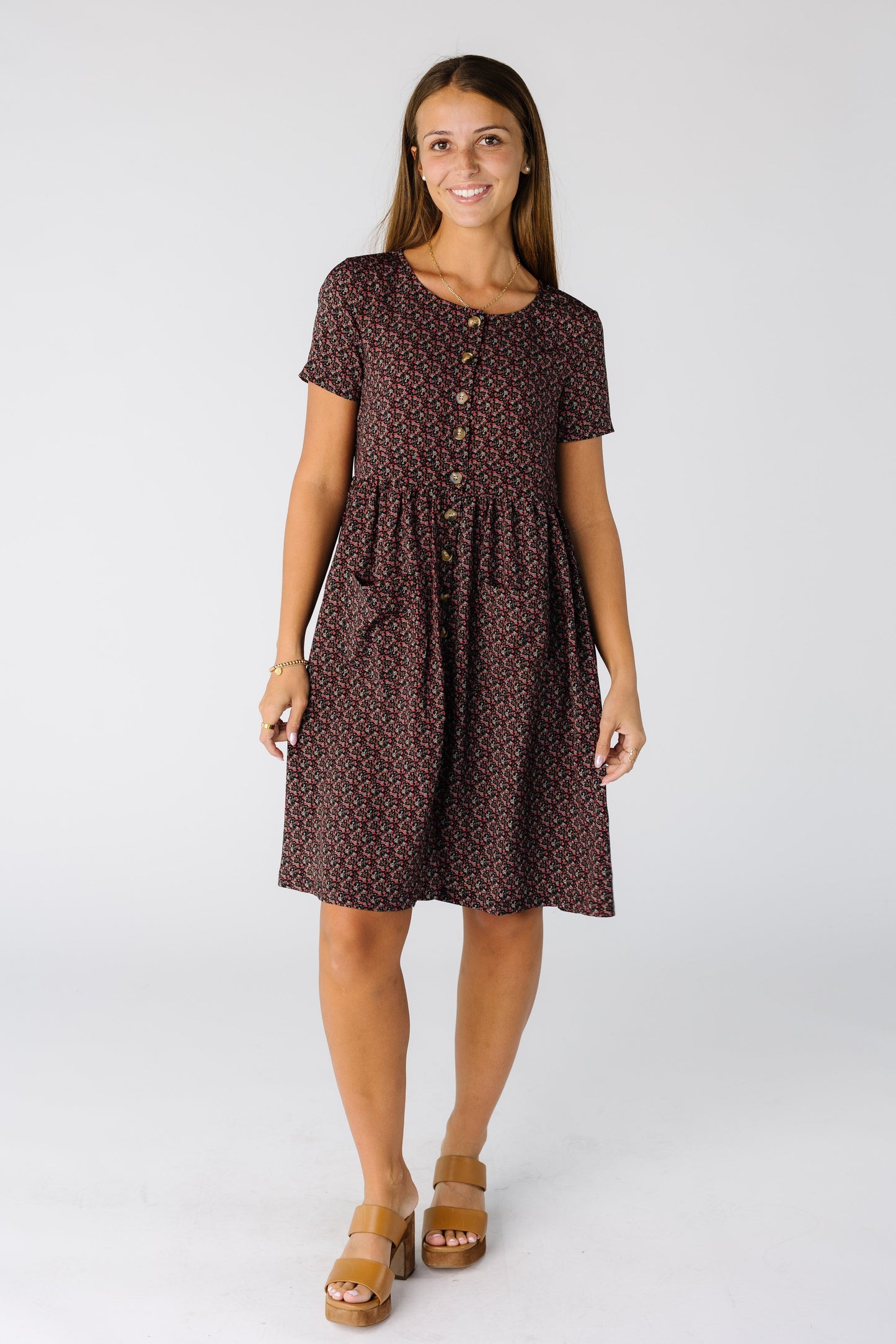 Woman wearing a knee length print dress with functioning buttons and 2 front patch pockets
