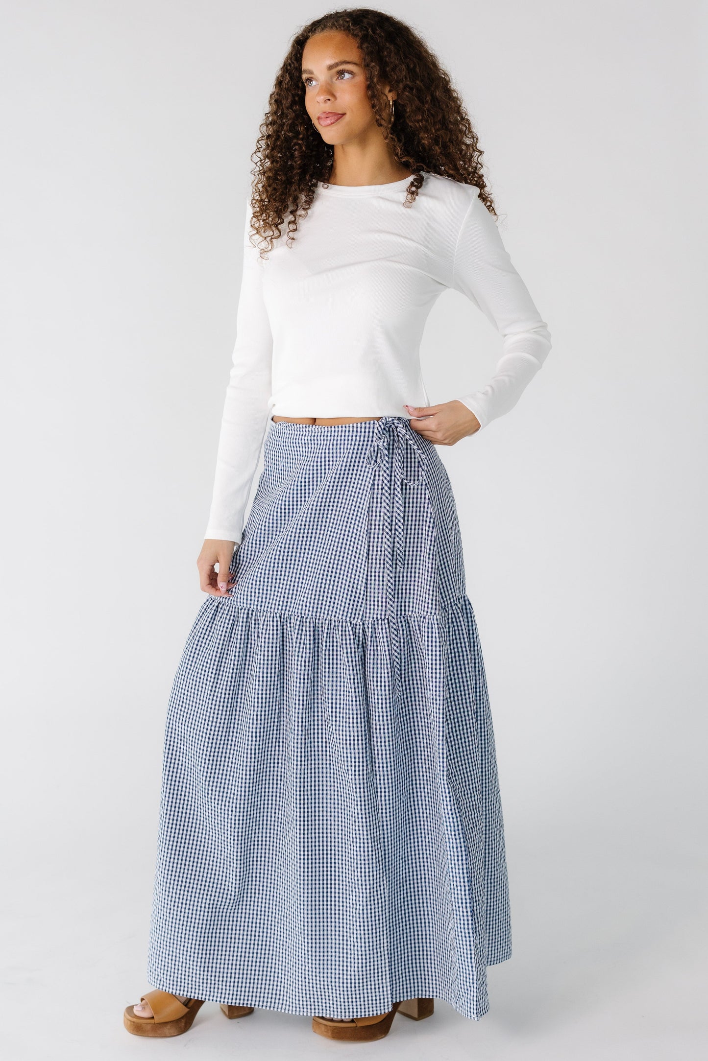 Teenage girl wearing a navy and white gingham wrap maxi skirt with a drop waist.