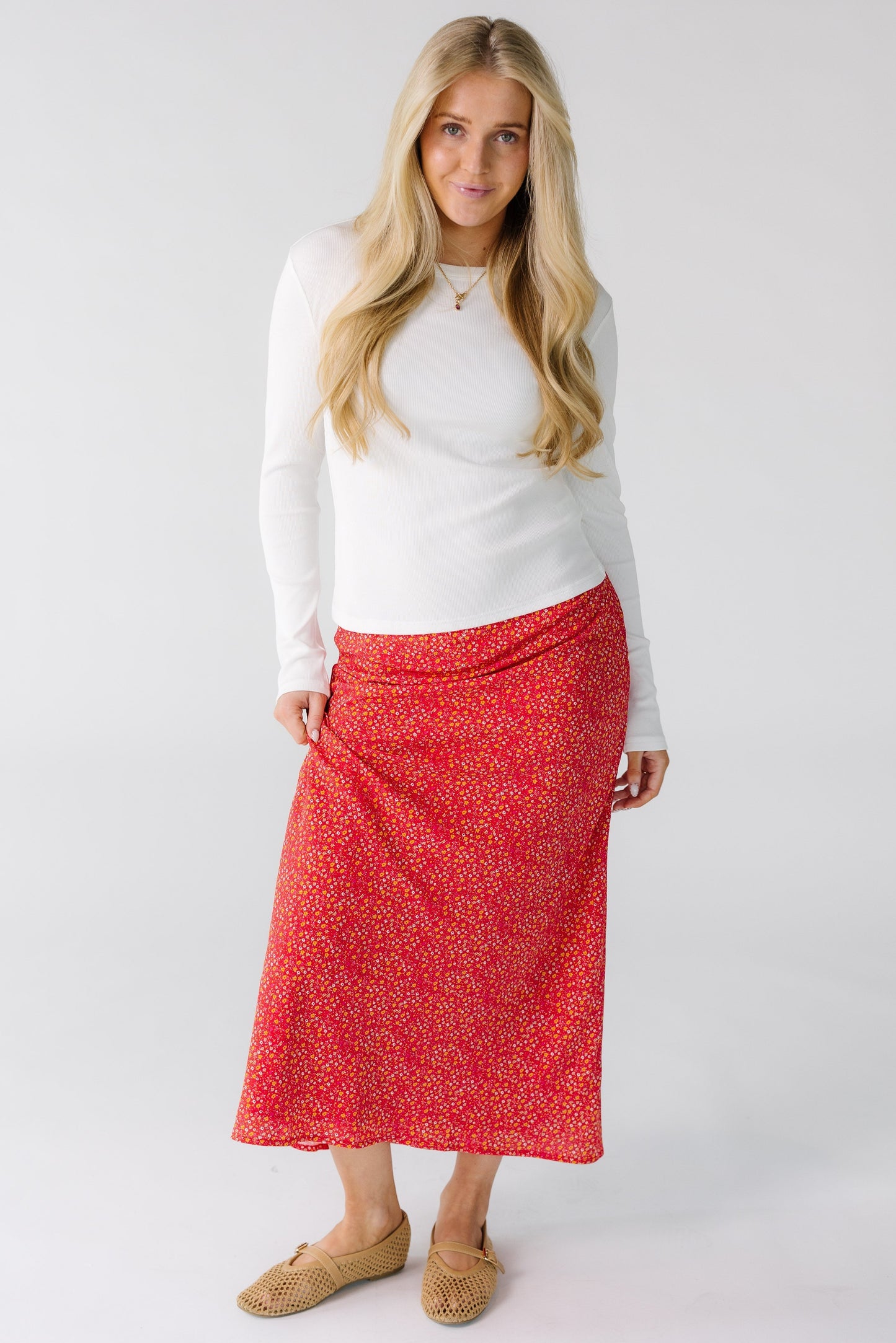 Woman wearing a red floral print A-line midi skirt.