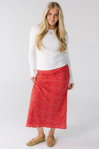 Woman wearing a red floral print A-line midi skirt.