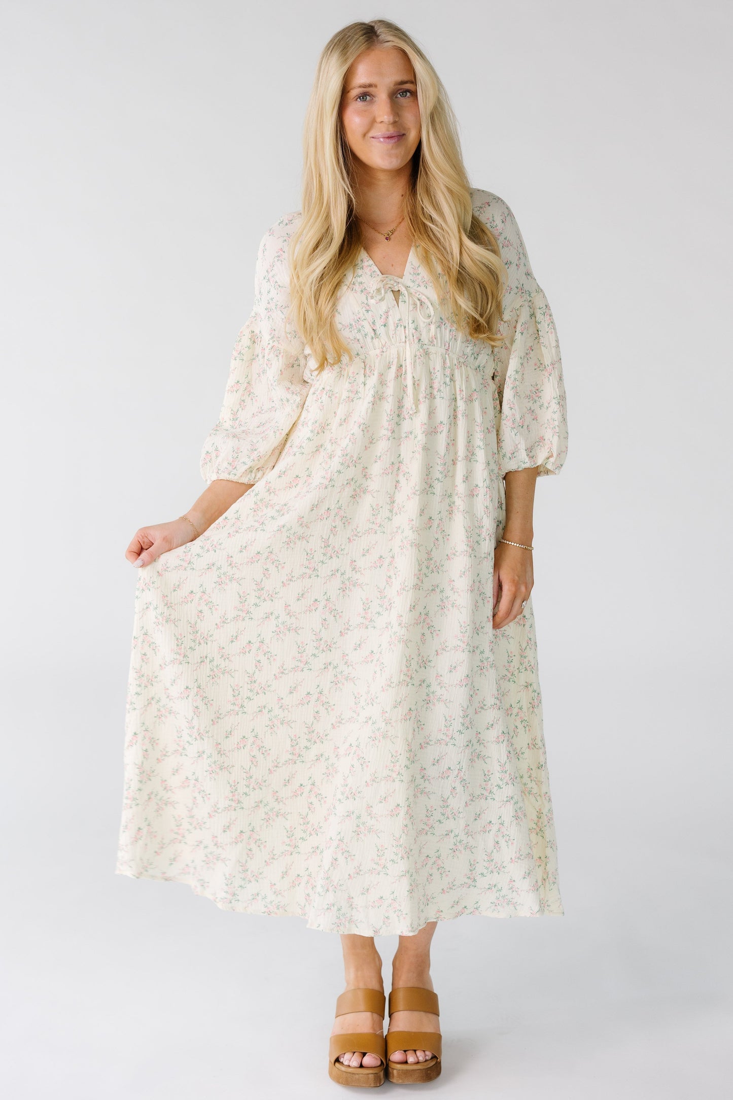 Woman wearing a modest ivory midi dress with three quarter length sleeves and an empire waist.