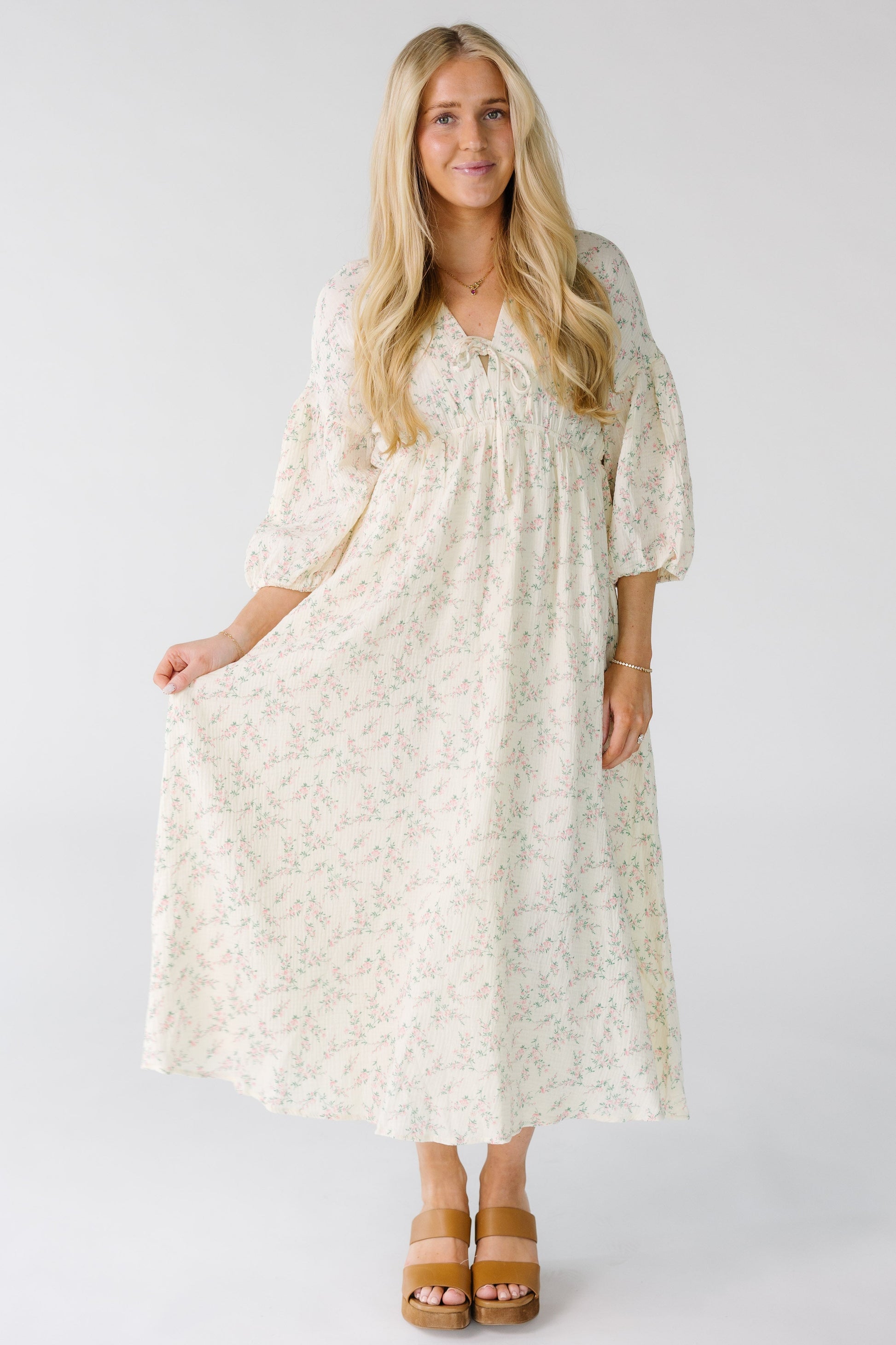 Woman wearing a modest ivory midi dress with three quarter length sleeves and an empire waist.