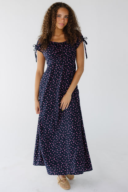 Young woman wearing a blue & pink floral midi-maxi dress with a drawstring-scoop neckline with short puff sleeves and an empire waist.