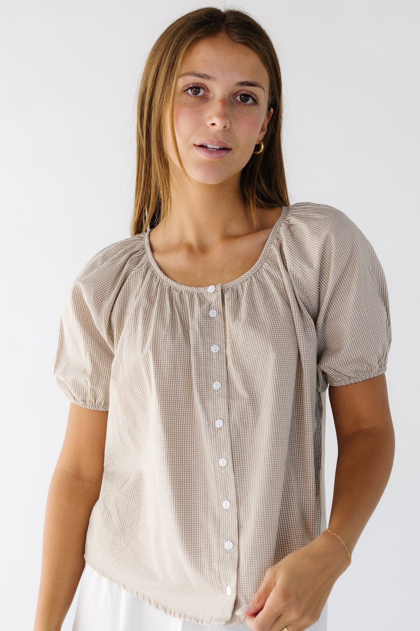 Young woman wearing a modest loose fitting button down blouse with a round neckline and short puff sleeves.