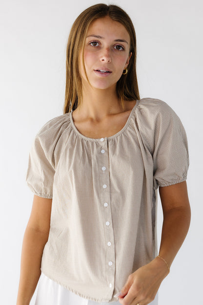 Young woman wearing a modest loose fitting button down blouse with a round neckline and short puff sleeves.