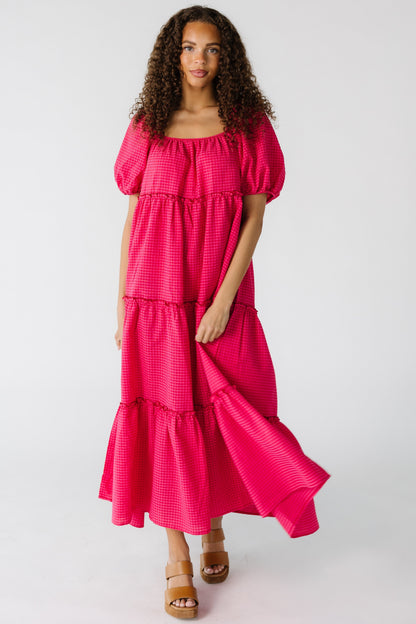 Teenage girl wearing a loose fitting pink gingham midi dress with short sleeves.