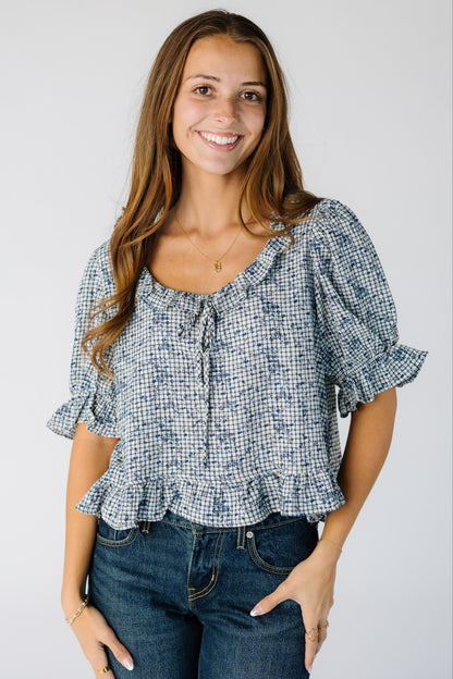 Woman wearing a modest blue plaid and floral top with a scoop neckline and short sleeves