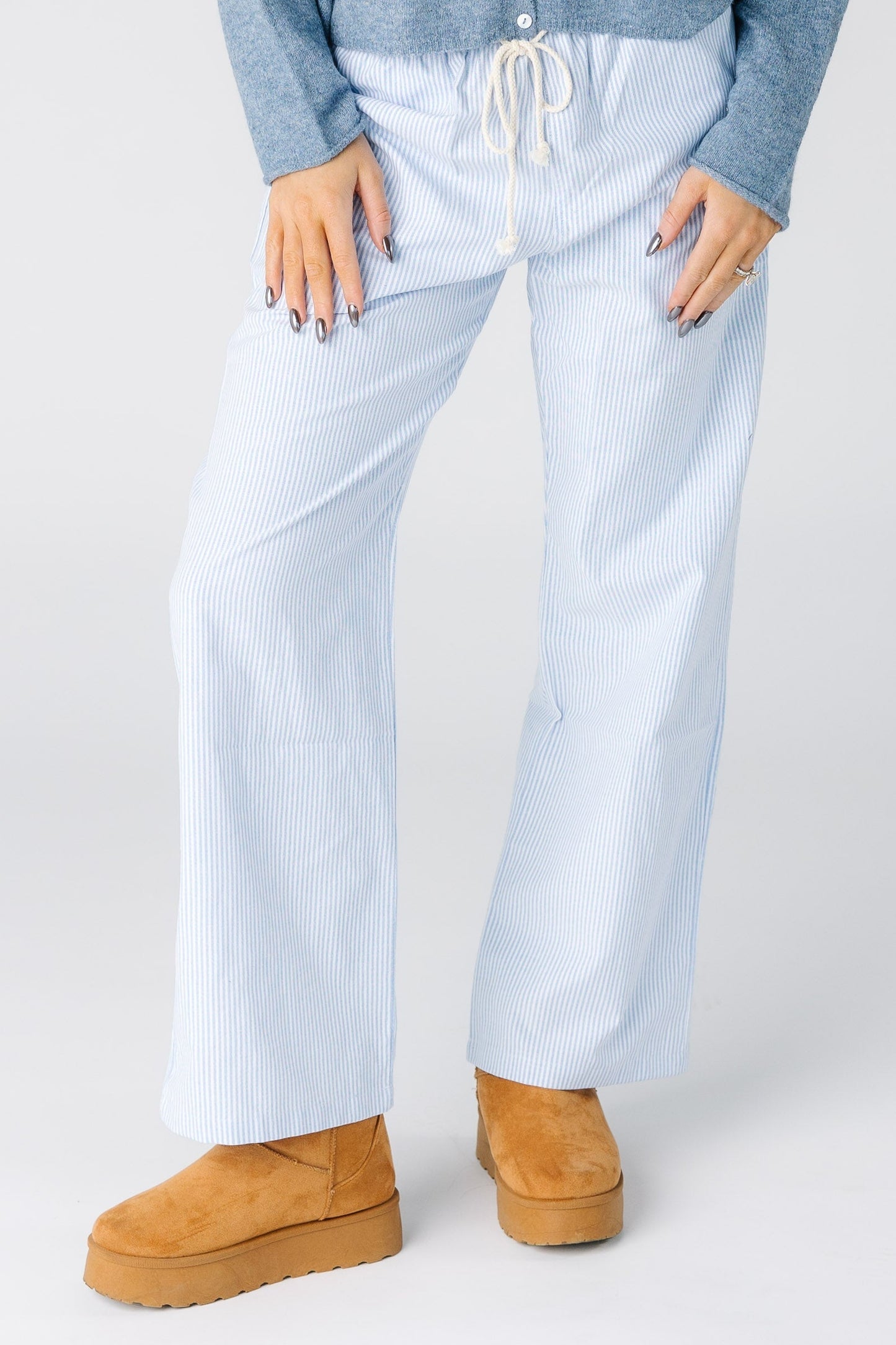 Woman wearing a pair of blue and white stripe pants with a drawstring waist