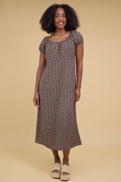 Young woman wearing a modest olive floral midi dress with short puff sleeves and wide scoop neckline.